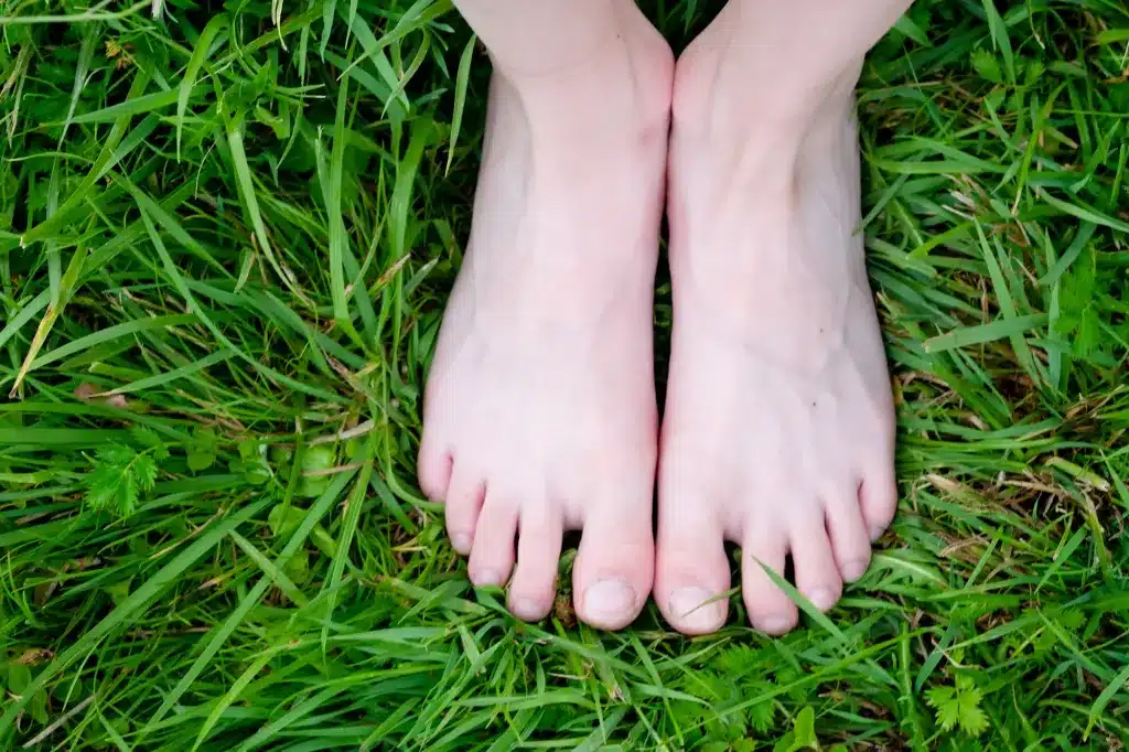 Bare feet standing on green grass. Somatic trauma therapy near Tigard, Oregon.