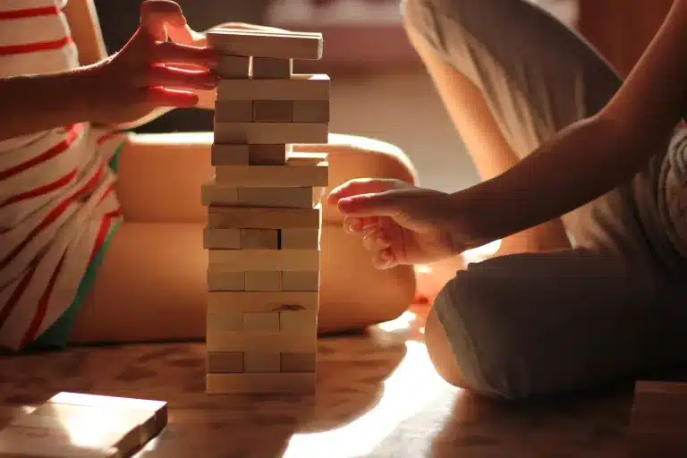 Hands building a wooden block tower on the floor. Deciding if play therapy is right for your child, from a counselor near Tigard, Oregon.