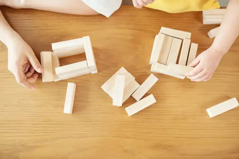 An adult's and a child's hands building with wooden blocks. Child and teen therapy near Tigard, Oregon.