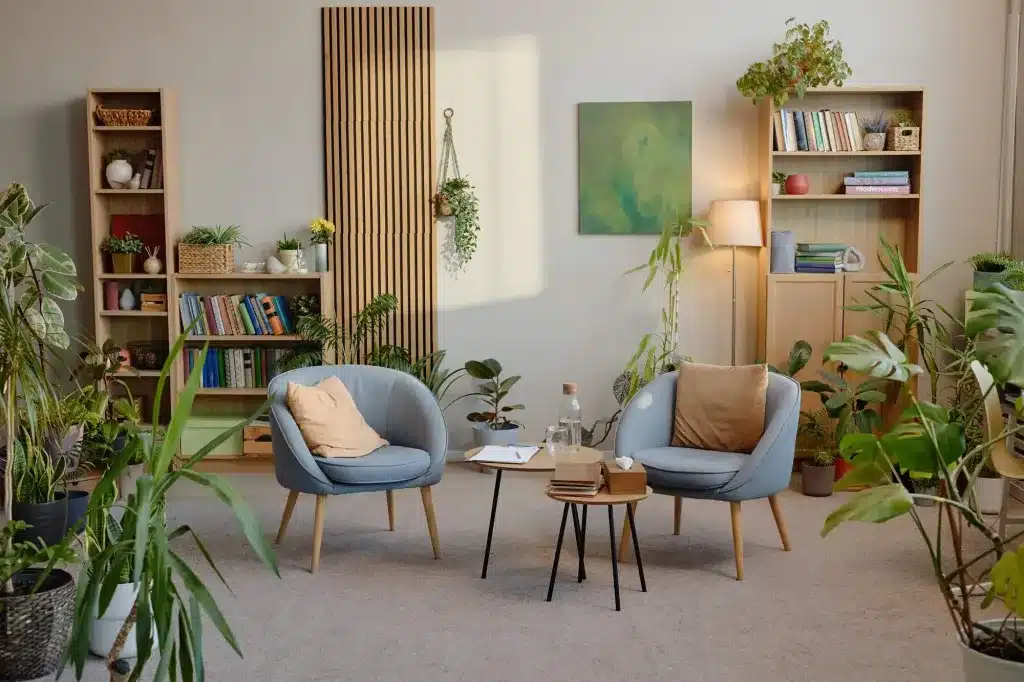 Two blue armchairs and a small table in a calm room with plants and bookshelves. Counseling for children, teens, adults and families near Tigard, Oregon.