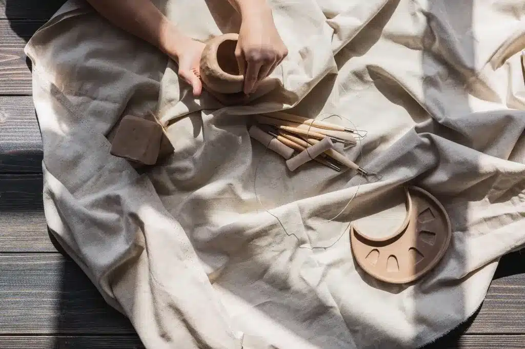 Hands shaping pieces of clay on a linen cloth. Play therapy for children near Tigard, Oregon.