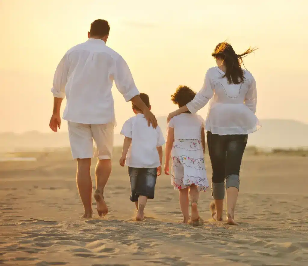 A family of four walking along a beach, seen from behind. Therapy for third culture kids and multicultural families.