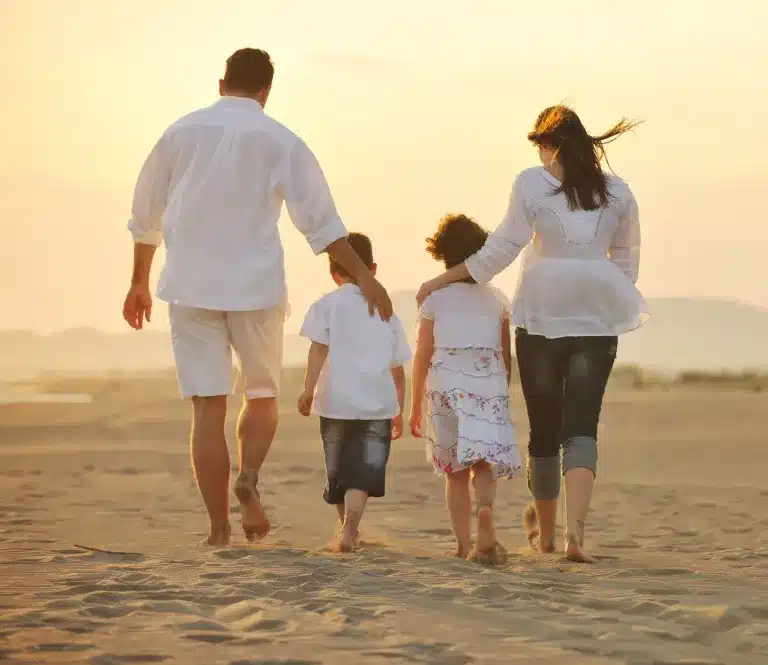 A family of four walking along a beach, seen from behind. Counseling for children, teens, adults and families near Tigard, Oregon.