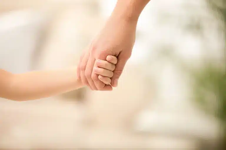 An adult's hand holding a child's hand