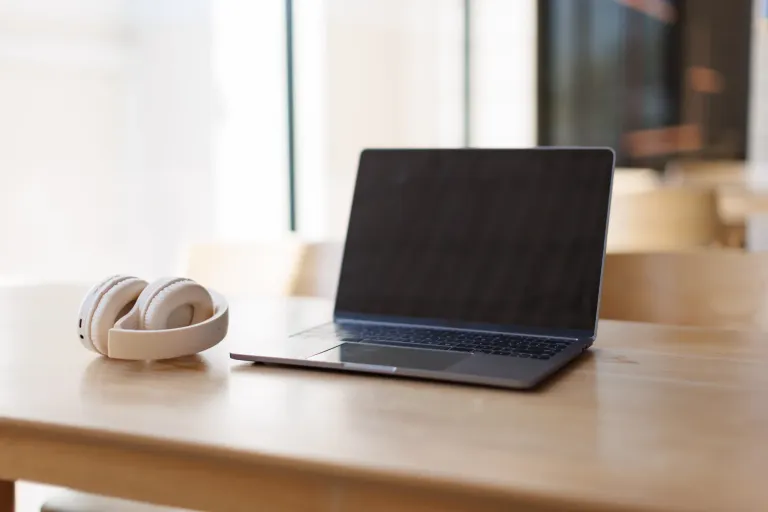 A laptop and headphones on a wooden table. Telehealth counseling anywhere in Oregon.