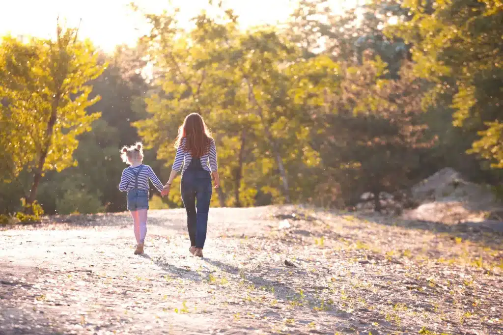 A mother and child walking hand in hand along a path, seen from behind. Therapy for third culture kids and multicultural families.