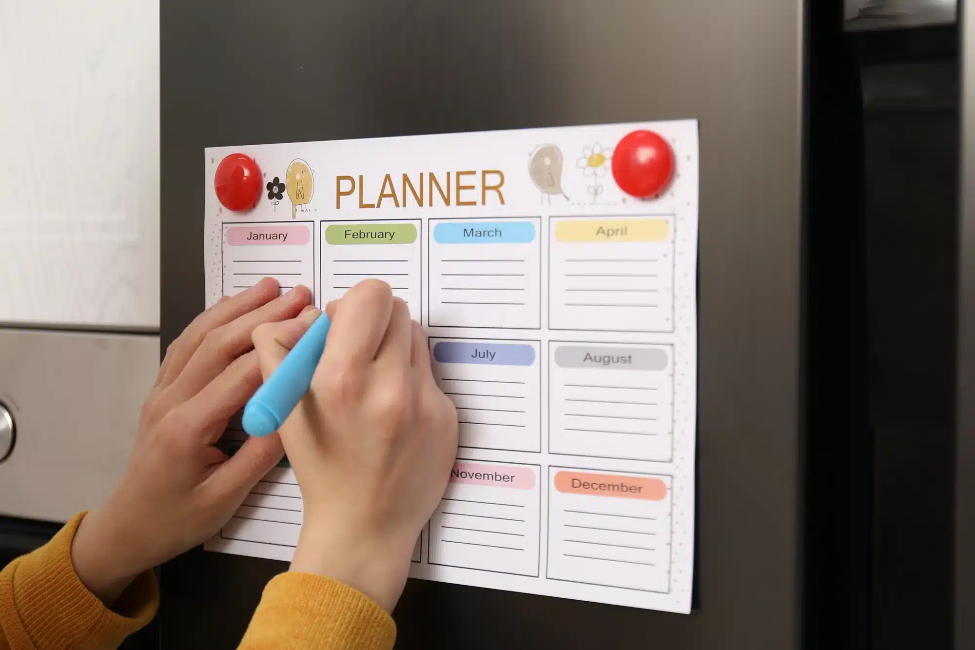 Hands writing on a family planner on the fridge. How often a child sees a therapist, from a counselor near Tigard, Oregon.