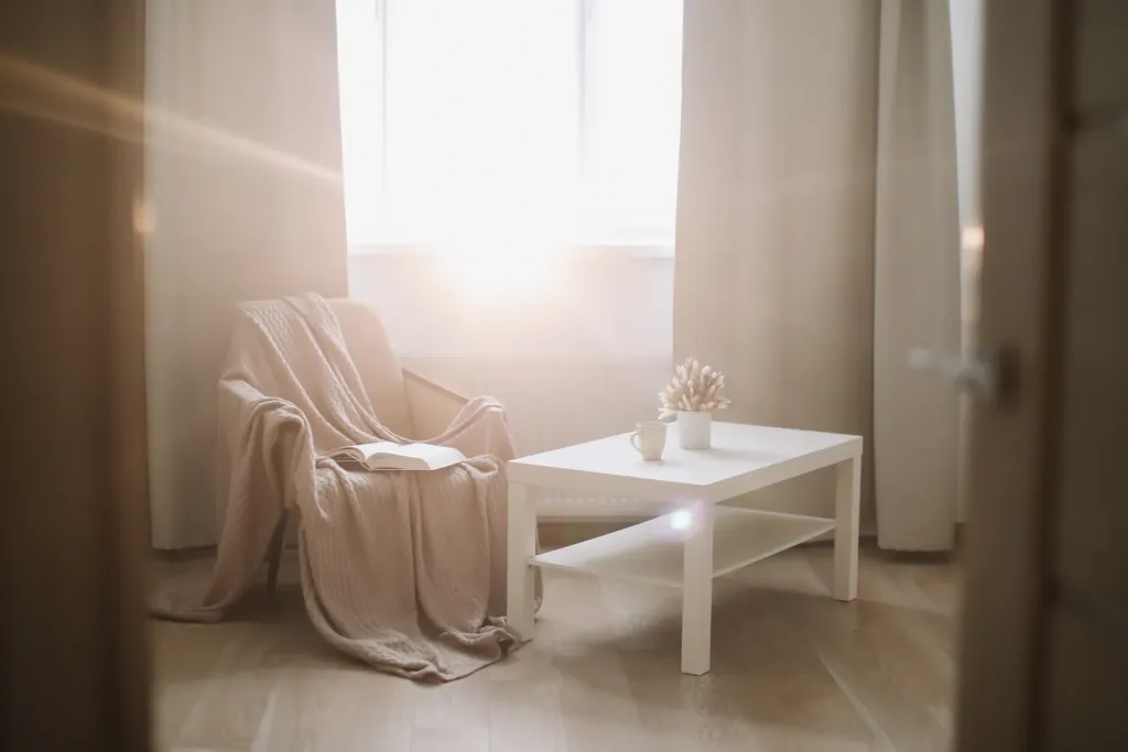 An armchair with a blanket beside a small table in soft window light. Counseling for adults near Tigard, Oregon.
