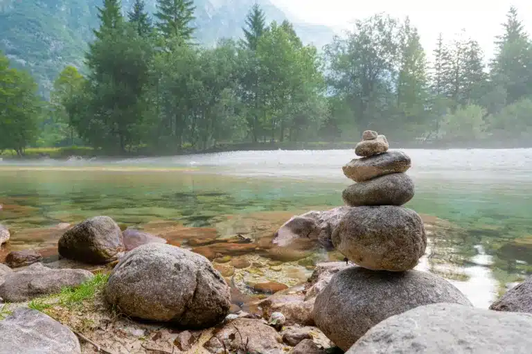 Stacked stones beside a river in a forested valley. Somatic trauma therapy near Tigard, Oregon.