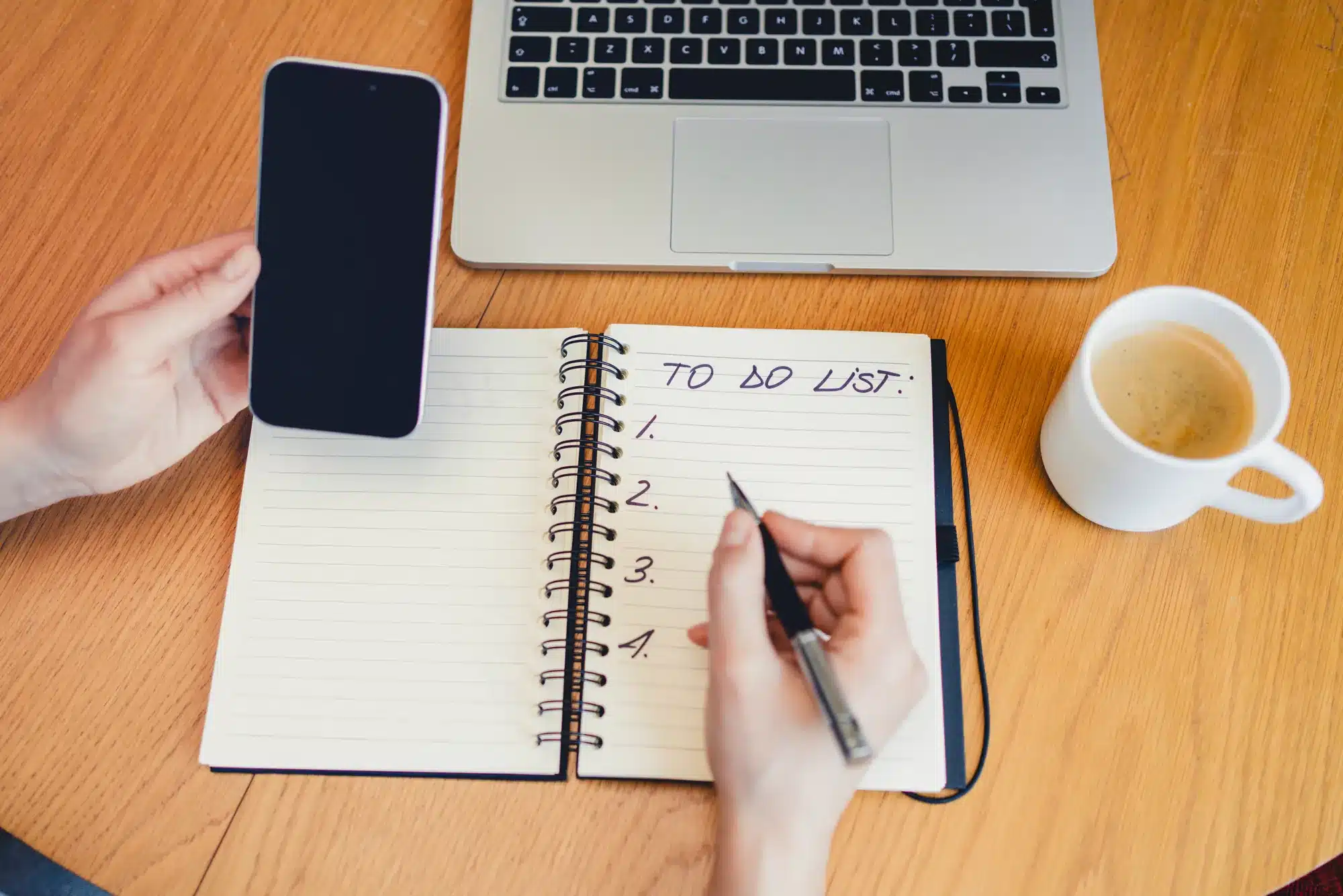Hands writing a list in a notebook beside a phone and a cup of coffee. Choosing a therapist for your child, from a counselor near Tigard, Oregon.