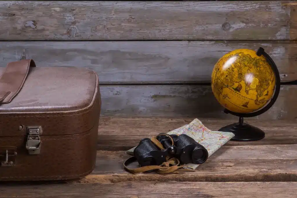An old suitcase, a globe, binoculars and a map on a wooden table. Life transitions counseling near Tigard, Oregon.
