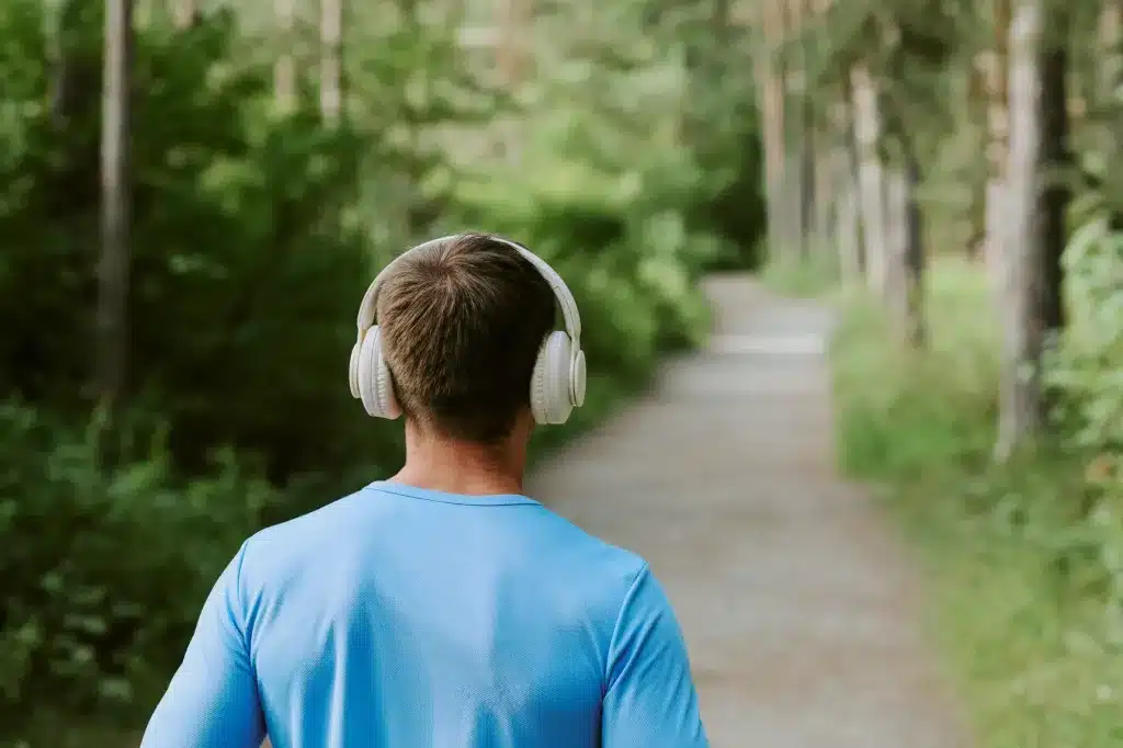 A young man with headphones walking a green path, seen from behind. Child and teen therapy near Tigard, Oregon.