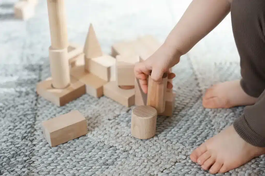A child's hands building with wooden blocks on a rug. Child and teen therapy near Tigard, Oregon.